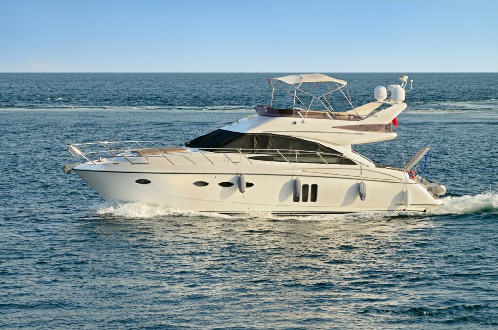 A white motor yacht glides on clear blue waters under a clear sky, its pristine surface a testament to expert paint protection film training.