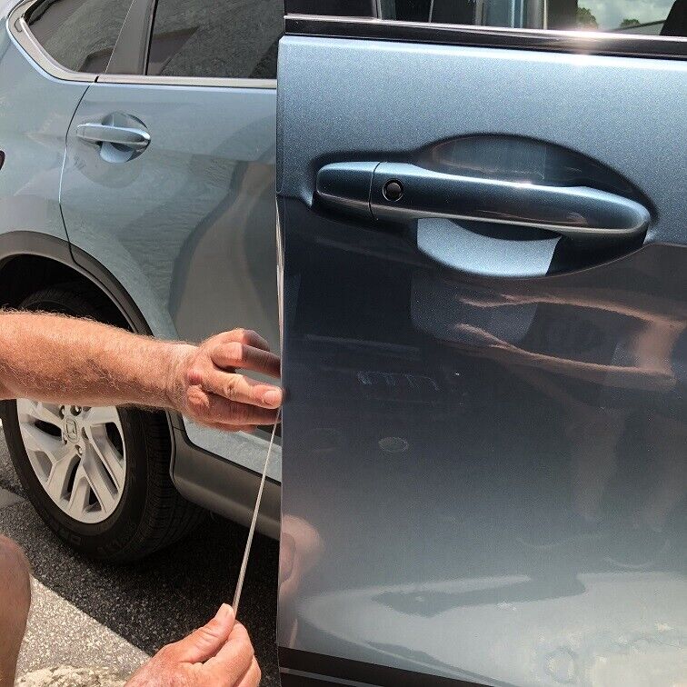 A person undergoing Paint Protection Film Training applies a protective film to the edge of a blue car door.