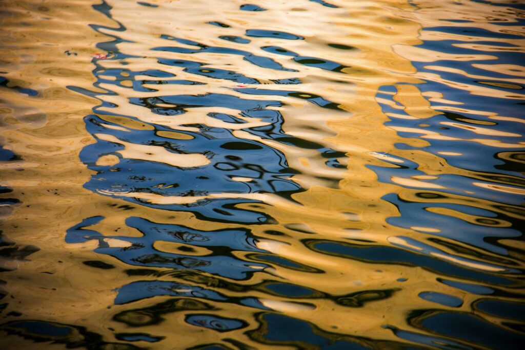 Rippled water surface reflecting blue and yellow light, reminiscent of a Paint Protection Film Training session with its precise and shimmering application.