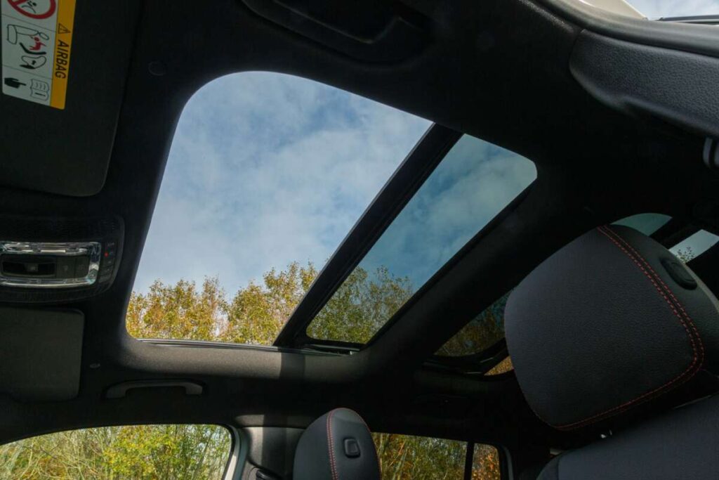 From the interior of the car, the panoramic sunroof offers a breathtaking view of blue skies and treetops. The experience is enhanced by a PPF Ceramic Window Tint, which ensures clarity while providing added protection against harmful UV rays.