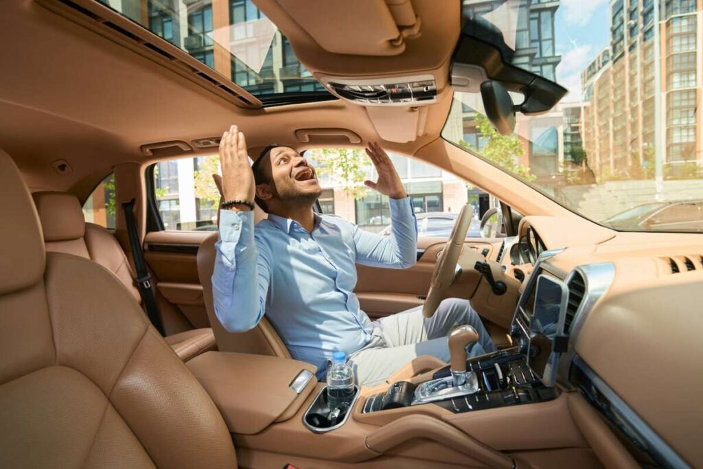 A man in a car, enveloped in the benefits of PPF Ceramic Window Tint, looks frustrated, gesturing with his hands up.