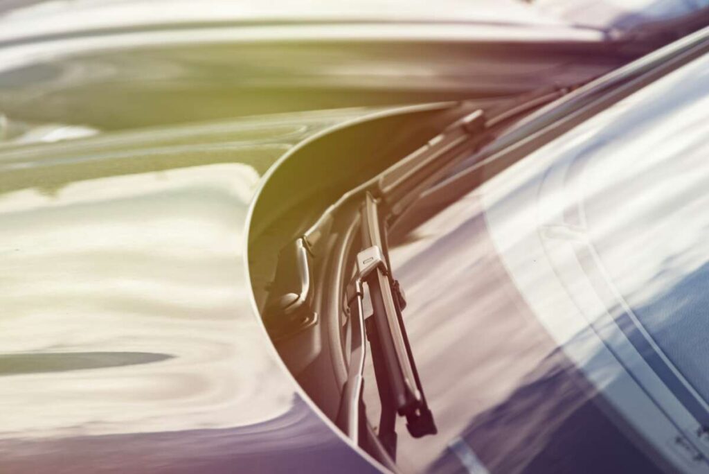 Close-up of a car windshield wiper, with expertise from Paint Protection Film Training subtly visible against a blurred background.