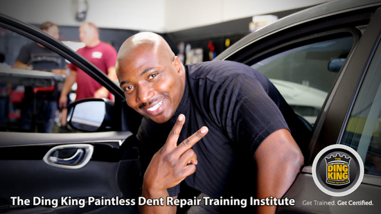 A smiling man making a peace sign while leaning on a car door inside an auto repair shop. Text reads: "The Ding King Paintless Dent Repair Training Institute. Get Trained. Get Certified. Ideal for Veterans seeking vocational rehabilitation.
